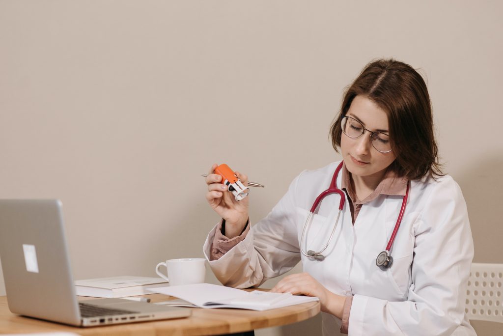 A woman in white coat holding a pen and paper.