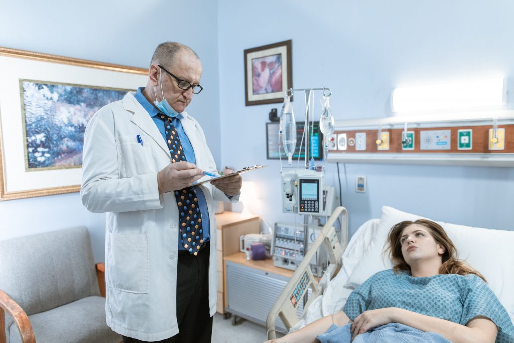 A doctor is standing next to a patient in the hospital.